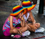 Sisters with colourful hats watching busker