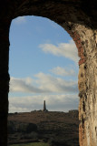 Monument on Carn Brea, framed by the window of a derelict tin mine