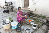 Washing her pots and pans in front of the house