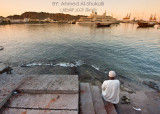 Man sitting next to Sultan Qaboos Port in Mutrah