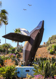 Birds flying over the breaching whale statue in Laguna Beach
