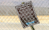 Warning sign behind a chain link fence in Tule Springs Fossil Beds NM