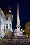 Lit Robba Fountain of the Three Rivers in the Town Square of Ljubljana capitol city of Slovenia at twilight with clock tower of 