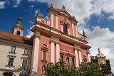 Clock tower and pink facade of Franciscan Church of the Annunciation topped by copper statue of Our Lady of Loretto Ljubljana Sl
