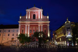 Pink facade of Franciscan Church of the Annunciation next to Urbanc House Luxury department store at dusk Preseren Square Ljublj