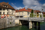 Columns on the Plecnik designed Cobblers Bridge over the Ljubljanica river with old and renovated houses Ljubljana Slovenia