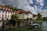 Historic buildings at Cankar Quay embankment of the Ljubljanica river at Fish Bridge with tour boat and Castle Hill of Ljubjlana