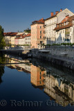 Bright buildings at the Ribja Brv modern footbridge reflected in the calm Ljubljanica river canal in Ljubljana Slovenia