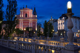 Lights on pink facade of Franciscan Church of the Annunciation and Central Pharmacy Preseren Square at dusk Triple Bridge Ljublj