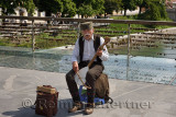 Old male street musician singing and playing a single stringed Gusle with bow on Butcher's Bridge over the Ljubljanica river Lju