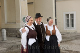 Man and two women in traditional dress standing in Pogazar Square at the Ljubljana Cathedral Slovenia