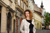 Pretty woman standing on cobblestone street of Upper Square with St Florian's steeple in old town of Ljubljana capital city of S