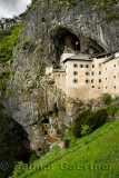 Grass hillside and cliff cave entrances at Predjama Castle 1570 Renaissance fortress built into the mouth of a cliffside cave in