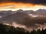 Misty sunrise in the mountains of Kamnik Savinja Alps and rolling fog in Skofjelosko Hills with St Thomas church near Ljubljana 
