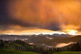 Golden sunrise in the mountains of Kamnik Savinja Alps and rolling fog in Skofjelosko Hills with St Thomas church near Ljubljana