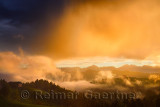 Golden clouds and fog at sunrise in the mountains of Kamnik Savinja Alps in Skofjelosko Hills with St Thomas church near Ljublja