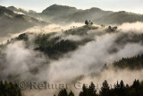 Rolling fog at sunrise in the Skofjelosko Hribovje Hills with St Thomas church on hilltop near Skofja Loka Slovenia