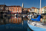 Marina at old fishing town of Izola Slovenia on the Adriatic coast with Parish Church of St Maurus tower and colorful reflected 