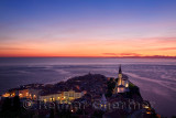 Purple light on the Adriatic Sea after sundown with lights on Piran Slovenia Courthouse City Hall St Francis church and St Georg