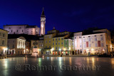 Lights reflected on Tartini Square Plaza in Piran Slovenia with Tartini statue monument, St. George's Parish Church with belfry 