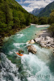 Kayaker shooting the cold emerald green alpine water of the Upper Soca River near Bovec Slovenia with Veliko Spicje mountain in 