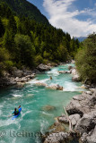 Kayakers shooting the cold emerald green alpine water of the Upper Soca River near Bovec Slovenia with Kanin mountains in the Ju