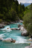 Kayakers paddling the cold emerald green alpine water of the Upper Soca River near Bovec Slovenia with Kanin mountains in the Ju