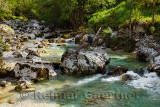 Man on karst rocks watching turquoise water of Vrsnik river in Spring Trenta Valley Vrsnica Gorge Triglav National Park Slovenia