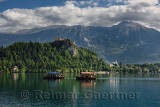 Traditional Pletna boats with colorful canopy on Lake Bled with Bled castle on cliff and St Martin church Sol massive of Karawan