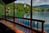 View of Bled Island Assumption of Mary pilgrimage church and wood Pletna boat oarsmen rowing tourists on Lake Bled Slovenia