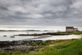 Church converted to a house on the Sound of Iona Martyrs Bay with beach and cloudy skies and sailboats Isle of Iona Scotland UK