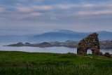 Granite stone ruins of the Bishops House next to Iona Abbey at dusk on Isle of Iona with view over Sound of Iona to Isle of Mul