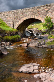 Red stone bridge in sun over Russel Burn river of Bealach na Ba road mountain pass on Applecross Peninsula Scottish Highlands Sc