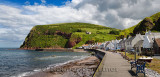 Row of white houses of Pennan coastal fishing village on North Sea in Aberdeenshire Scotland UK with Black Hill sea cliff