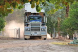 A very big truck laying down new gravel on our driveway, entering our house yard.