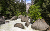 Distant view of Vernal Falls over boulders in the angry Merced River in Yosemite National Park
