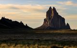 The setting sun lights up the shear rock cliffs at Shiprock