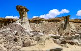 Large hard rock capped hoodoos near a rock wall in the Bisti Wilderness