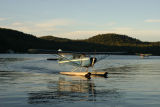 A seaplane is docking while the other one lands on the water of Seventh Lake.