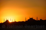 Sun setting behind Blue Mosque with Hagia Sophia in silhouette on the Bosphorus Istanbul