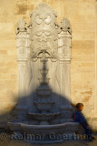 Young boy at stone fountain with shadow of a dome at Eyup Sultan Mosque Istanbul