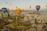 Many hot air balloons over the Red Valley with cave churches Cappadocia Turkey at dawn with moon