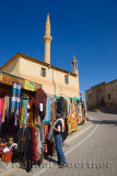 Female tourist shopping for clothes in Mustafapasa village with minaret and university Cappadocia Turkey