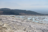 Dry and spring water filled travertine terraces with mountains of Denizli at Pamukkale Turkey