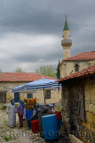 Local women talking at an olive stand in ancient hillside village of Yesilyurt Turkey with minaret