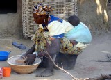 Mother doing housework while carrying her baby, Burkina Faso