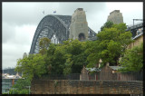 On a rainy and overcast day, the Harbour Bridge rises above Sydneys Rocks district