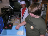 The teacher looks on as Brendon forms the rice, after cutting some tuna.
