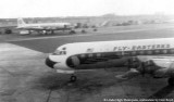 1959 - an Eastern L-188 Electra taxiing away from Concourse 5 with a Pan American DC-7 sits at Concourse 4
