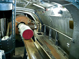 Inside a gun turret: Loading 104 pound bags of powder into breach of 14 inch gun.  Full charge= 4 bags.